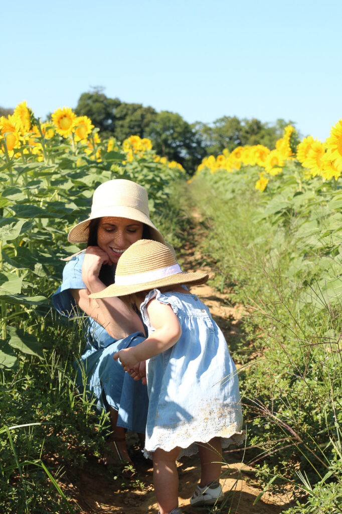 kneeling with Austyn in the sunflower fields